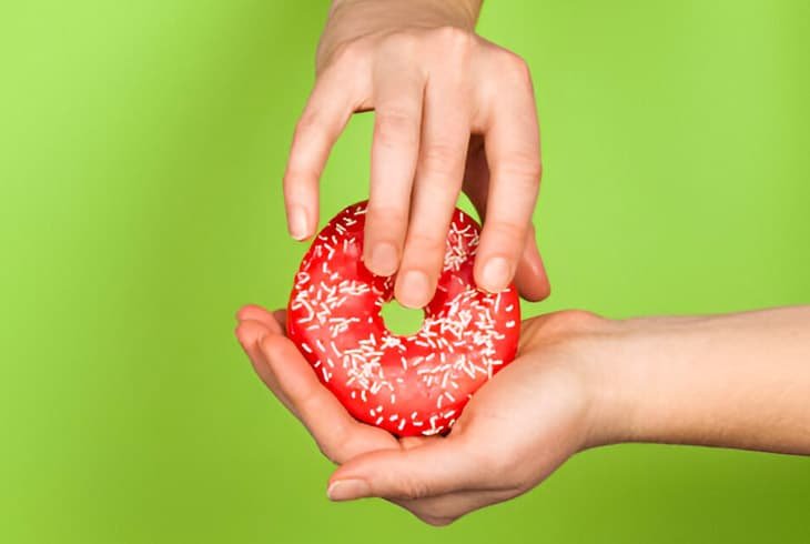 Manos tocando una rosquilla sobre un fondo verde